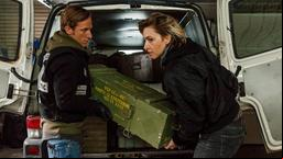Chris Blome (Merlin Leonhardt) und Nina (Kim Riedle) laden Waffen aus dem Transporter.