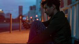 Der Geflüchtete Najim (Shadi Eck) scrollt durch sein Handy.