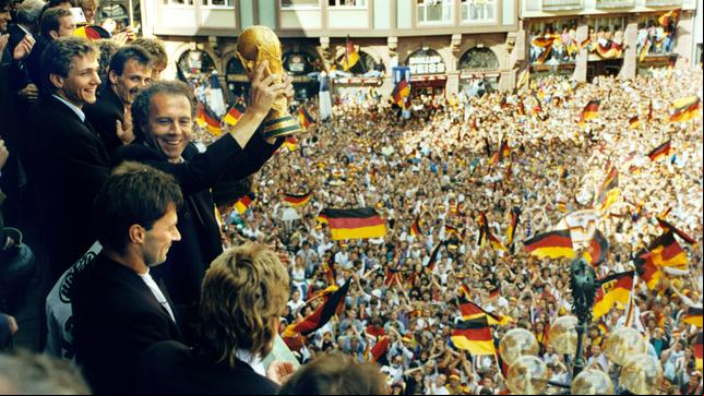 Viele tausend Menschen bereiten den Spielern der deutschen Fußball-Weltmeistermannschaft am 09.07.1990 auf dem Römerberg in Frankfurt am Main einen begeisterten Empfang mit viel Jubel und einem Meer an deutschen Fahnen. 